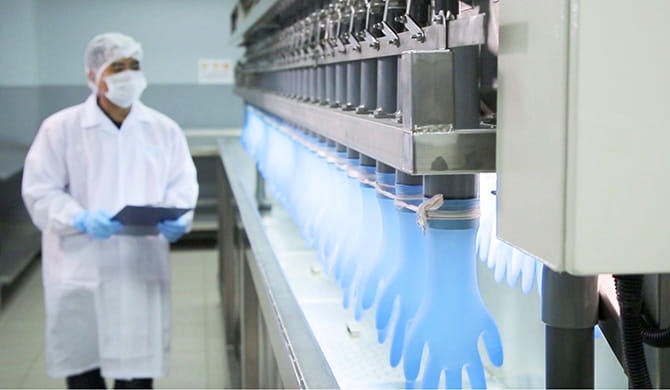 A worker in a lab coat operating a machine in a laboratory.