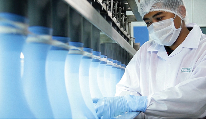 A worker in a lab coat operating a machine in a laboratory.